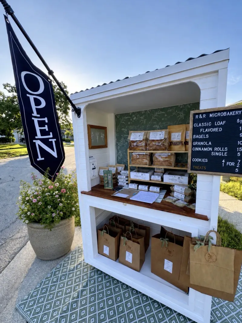 R&R Microbakery's stocked white self-serve bake stand with its open flag